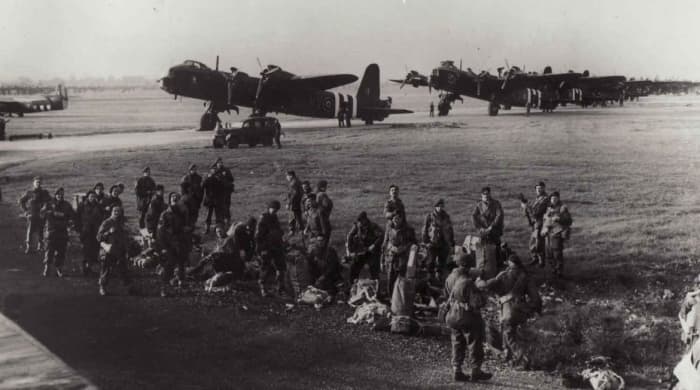 3. Platoon, 21st Ind. Parachute Coy. emplane at Fairford, Gloucester. Behind them are Short Stirling Bombers taken from bombing duties, assigned to tow gliders - vertical stripes were added to fuselages and wings for recognition as Allied aircraft