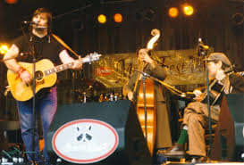 Steve Earle standing at far left, with Norman Blake, seated at far right, at the North Carolina Merlefest festival in the late 1990s.