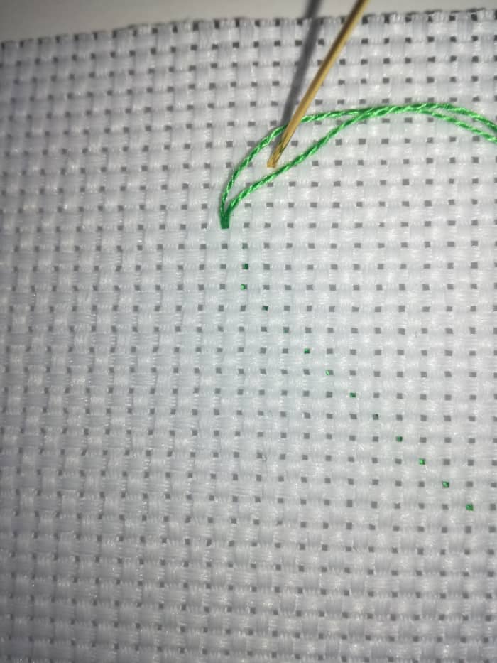 Image 1. Part the thread with the tip of your needle before inserting your needle into the opposite corner of your first stitch.