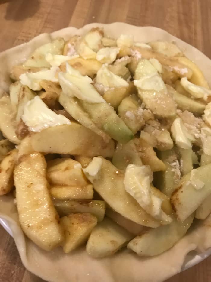 Dot the apples with butter. Line a 9 inch pie dish with pastry, and transfer pies to the dish. Move the apples around so they leave as little air space as possible, then top with a second crust.