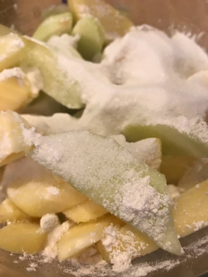 The sugar enhances the sweetness of course, and the flour helps thicken the juices that will cook out of the apples.