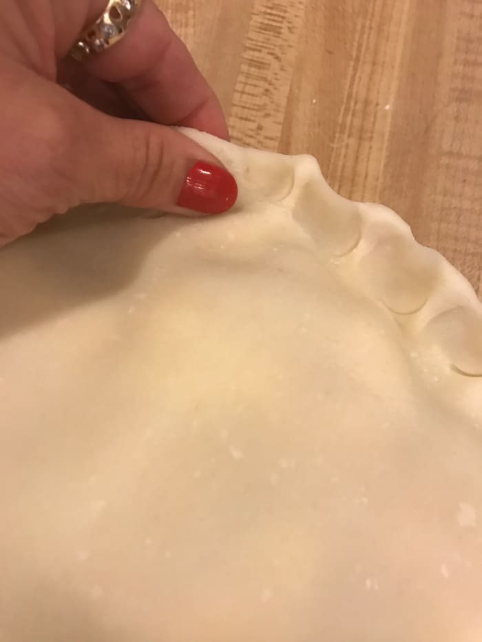 Crimping the edges does a couple of things. It's pretty - and pretty food tastes better. But it also seals the juices into the pie, so there's less chance of spillover in the oven.