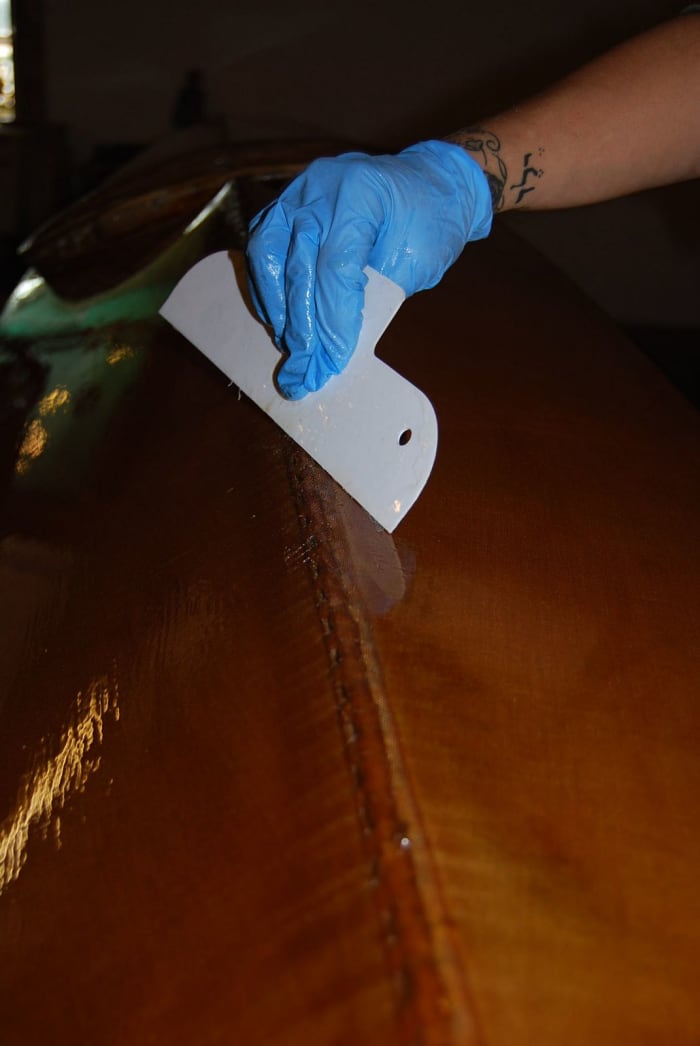 Applying the second coat of Verithane (note gloves and disposable scraper); also note tidy center seam where rolled fabric is stitched down.