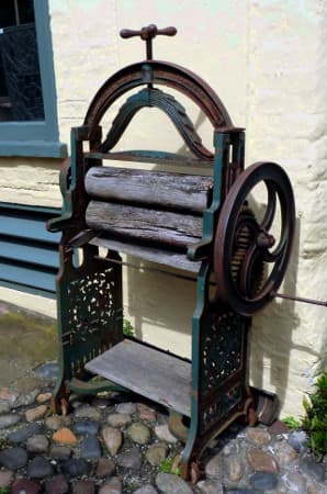 You can see the handle that controls the width of the space between the rollers, on the top of the mangle