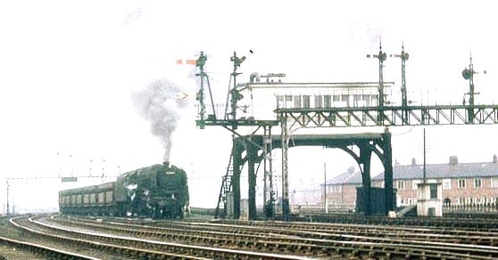 Box on stilts :9F 2-10-0 and Iron Ore bogies from Tyne Dock for Consett pass Green Lane near Washington, Co. Durham. Note the signal gantry and long twin bracket this side of the elevated box.