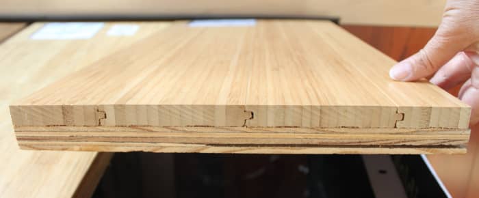 This is the edge of a flooring sample of solid vertical bamboo mounted on a piece of plywood.