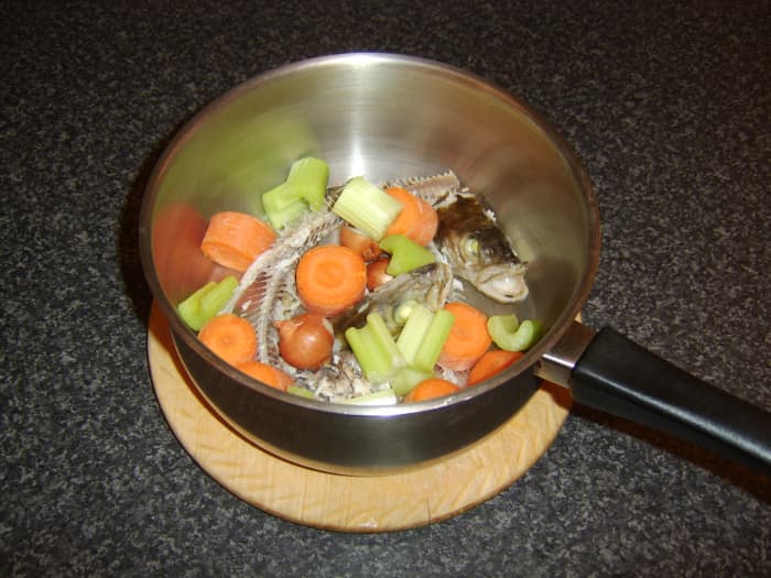 The fish heads and bones are added to a large soup or stock pot with the principal vegetable ingredients for the stock