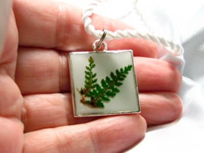 Jewellers like to produce dried, pressed flowers fast and set them in resin to create jewellery like this pendant.