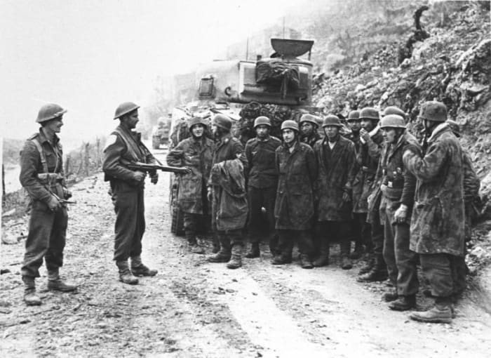 New Zealanders hold German paratroopers near the abbey ruins - from the looks on their faces the POWs look relieved
