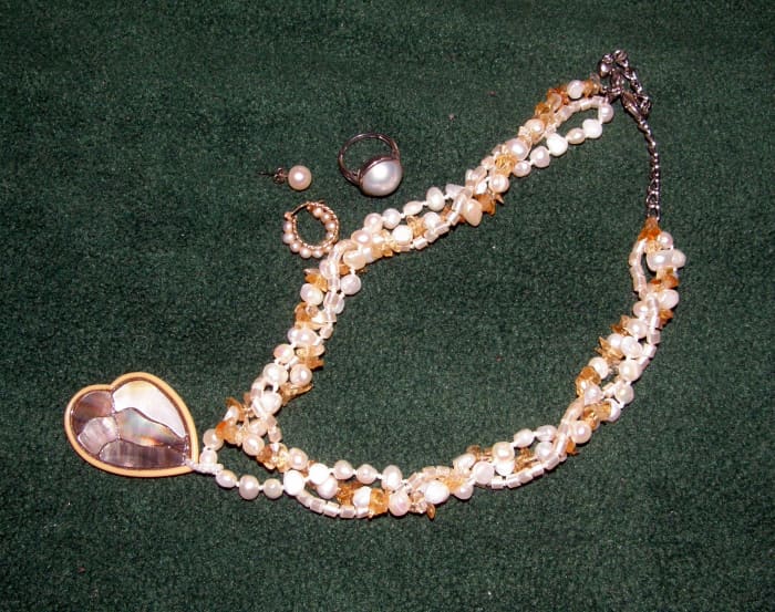 White pearls and citrine necklace. Beside it are a pearl stud, a pearl hoop earring, as well as a Mabe pearl ring.