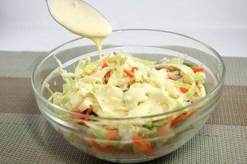 Use a large spoon and mix your cole slaw dressing into the slaw, carrots, peppers and onions and stir well.
