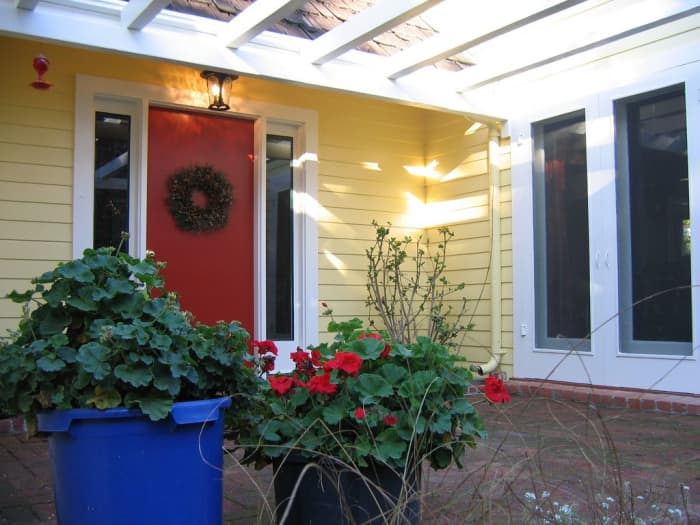 A bright red front door pops off the cheery butter yellow body of this farmhouse in Saratoga, California.
