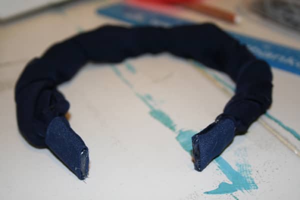 To finish off the look, I cut 2.5" x 4" pieces (2) of the sturdy material I first used to cover the ends of the headbands. I used an iron to give each piece some nice edges, then glued each strip around each end.
