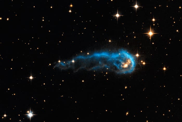This light-year-long knot of interstellar gas and dust resembles a massive caterpillar. Harsh winds from extremely bright stars are blasting ultraviolet radiation at this "wanna-be" star and sculpting the gas and dust into its long shape. The culprit