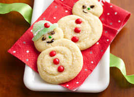 Snowman cookies made with two sugar cookies, red hot or M&M buttons, gum drop hats.