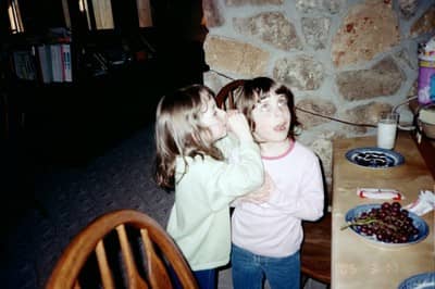 My daughter whispers a secret to a friend on a play date while snacks are served on blue willow china