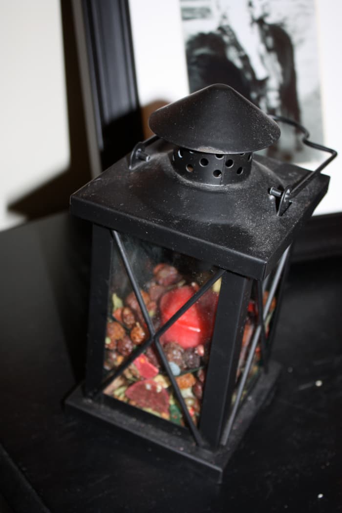A rustic iron lantern filled with a candle and potpourri