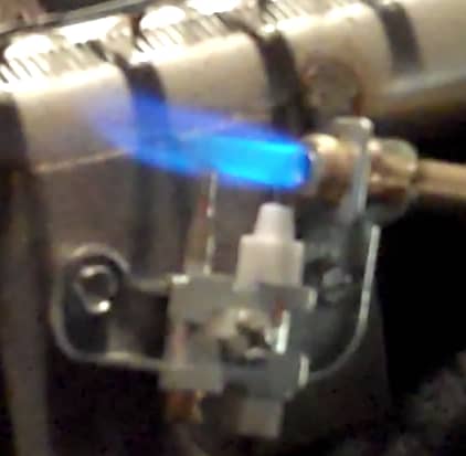 Ventless gas fireplace close up of pilot assembly showing the pilot flame, thermocouple and ignition electrode.