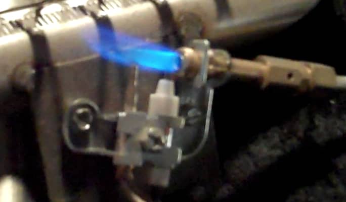 Along the pilot gas line to the right of the flame in this image there is a small hole in the brass sleeve.