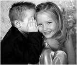 Happiness is best when shared - two children sharing a smile with the boy whispering into the blond little girls ear