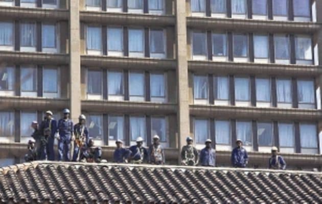 Construction workers watch strikers march through Johannesburg. Economists are warning of a global double-dip recession and say unions aren't helping SA lure foreign investment