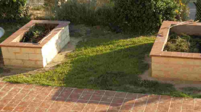 the same two raised bed gardens later in the season (the grass has grown back) partially filled with garden waste to make compost