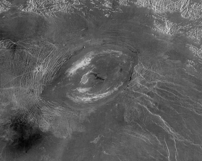 Sacajawea Patera is a 215 km (133 mile) wide. 1200 m (4000 ft) deep caldera in Ishtar Terra region. The river-like patterns in the lower right of the image are believed to be rift fractures through which magma has escaped in the past