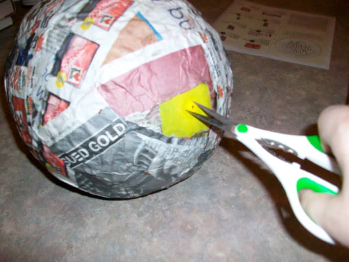 When the papier-mâché is fully dry and hard, snip a hole in the balloon through the space that you left open for putting the candy in.