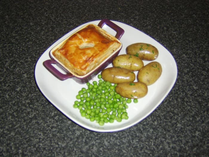 Braised oxtail and fresh oysters form the filling for this puff pastry pie which is served with chive buttered new potatoes and garden peas