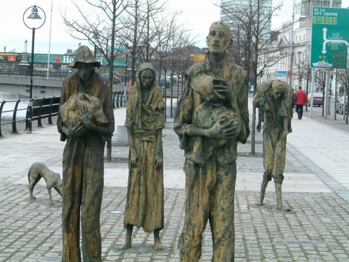 Customs House Quays, Dublin. Painfully thin sculptural figures, by artist Rowan Gillespie, stand as if walking towards the emigration ships on the Dublin Quayside.