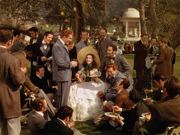 Scarlett surrounded by eager admirers, all begging to fetch her some food @ Twelve Oaks picnic. She chooses Charles Hamilton, making him fall even more in love with her. But she sees Ashley & Melanie walking in the garden & loses her appetite.