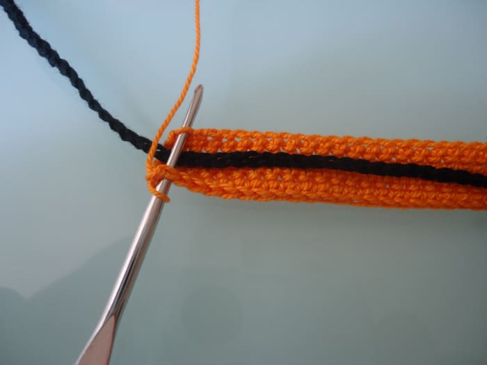 After placing the tie in the middle of the cape, insert hook through both thickness and sc over the folded work to close the opening.