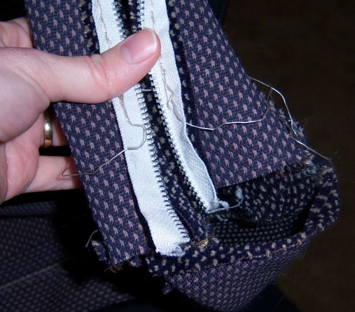 When removing a zipper, I always start at the open end. You can start at the closed end, but I find removing the stitches at this point easier.