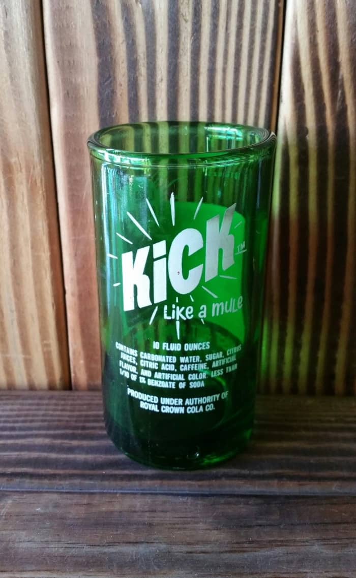 The back side of the Yava Glass, this is an Up-cycled Kick Like a Mule Soda Bottle Glass 4.5 inches tall, holds 6 fluid ounces, green glass with multi colored screen print