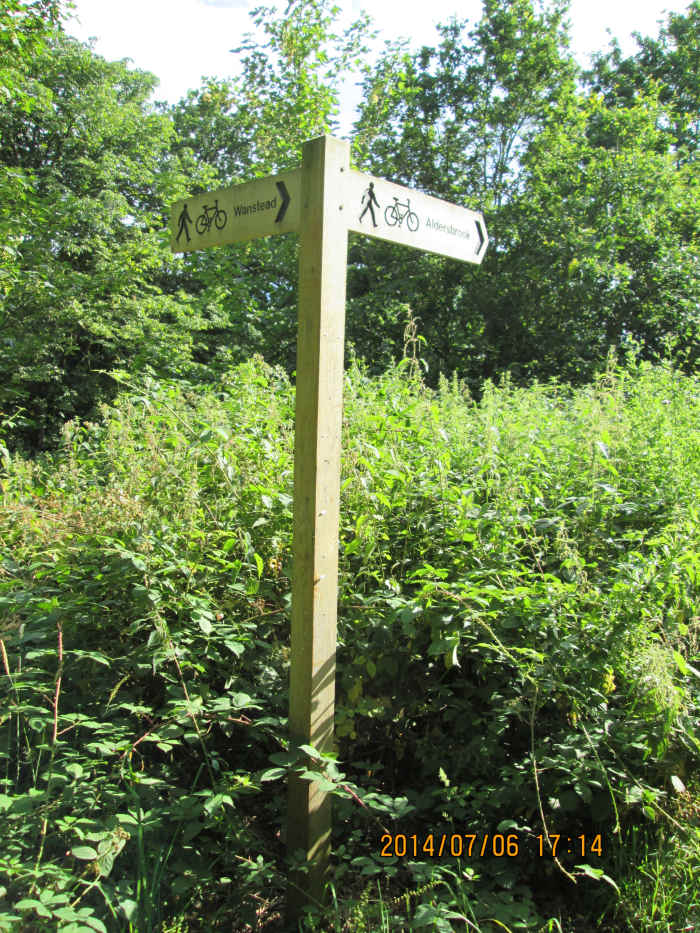 Cycle track signpost erected before 2012 London Olympics points one way to Wanstead, the other to Stratford via Aldersbrook