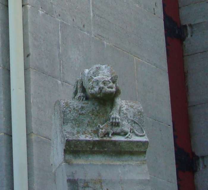 The cat grabbing a mouse can be interpreted as the intelligence protecting the knowledge from predators like the mice who come to eat and destroy the documents carefully guarded within those walls.