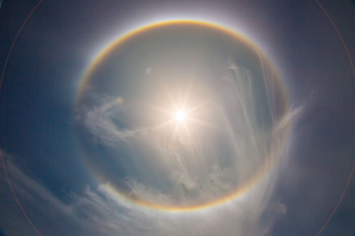 This Sun Halo clearly shows the rainbow-like circle that is indicative of Sun Halos and lens flares that might be mistaken as planets around the Sun. Science explains this as caused by ice particles in the atmosphere, might there be another cause?