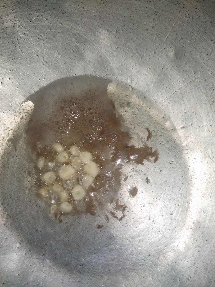 In a pan heat oil, ghee or butter. Add cumin seeds and chopped garlic, saute till raw smell of garlic goes away.