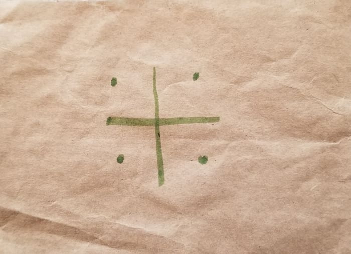 Step 1: Draw a plus sign with four dots at the corners. This process is pictured with separage squares cut from a paper bag, but is meant for you to coplete on the same piece of paper.