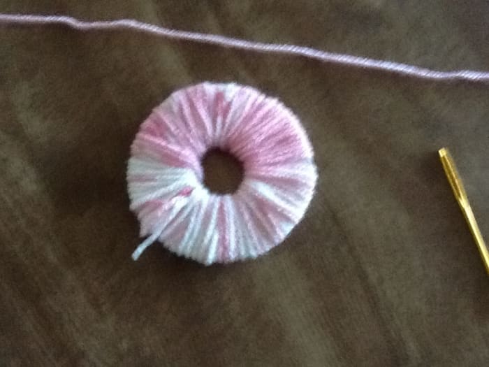 Completely cover the doughnut with the yarn. The more yarn you use the fuller your pom pom will be.