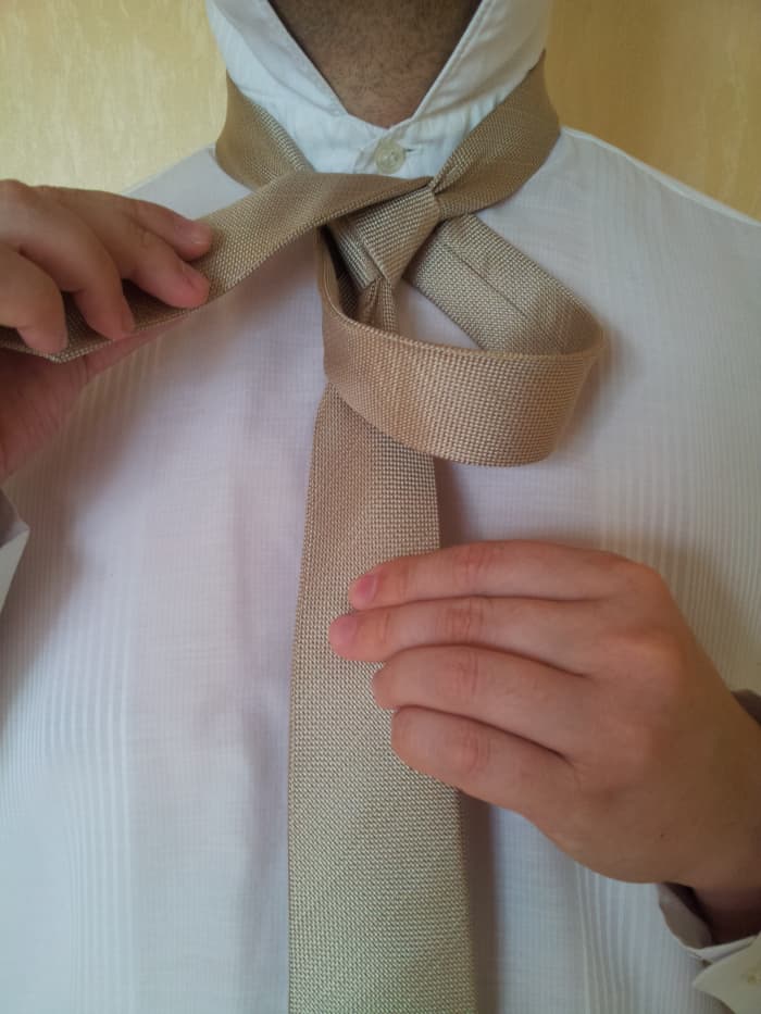 Step 6. Bring the narrow end over the center in front and go up through the middle from the inside of the loop.