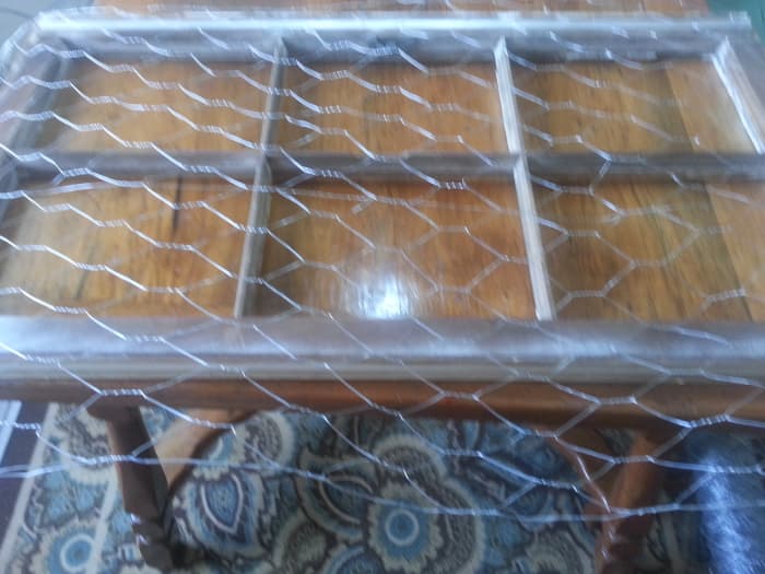 Stapling chicken wire on back of old wood window without glass to make a message / picture board.