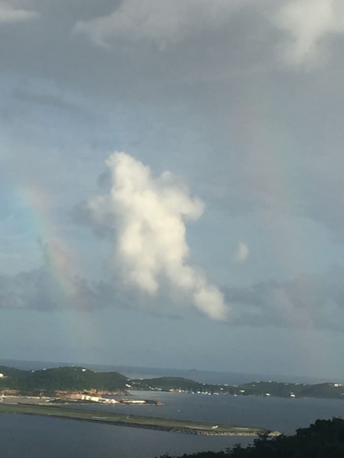 September 23, 2016 @ 5:20pm. St. Thomas USVI. This picture was taken over the Cyril R. King Airport. The caption is very interesting, It appears to be two rainbow with a cloud centered in a shape of a bear, perhaps or an angel.