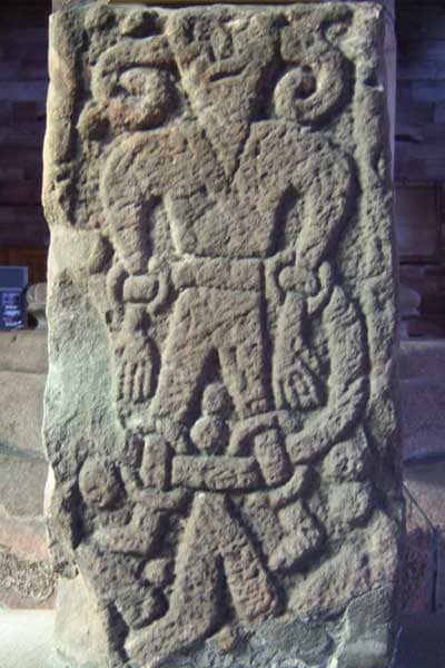 Stone carving of a bound and chained Loki at Kirkby Stephen in eastern Cumbria - he escapes as a salmon only to be caught and chained again, the jaws of his son Jormungand dripping poisonous saliva on his forehead