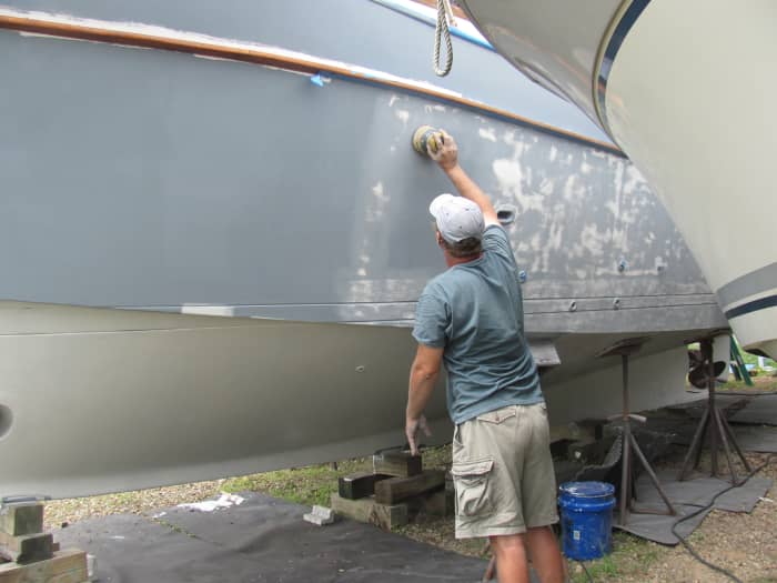 Another coat of barrier paint (white) has been applied to the bottom. Luke is still sanding the hull above the waterline smooth to prepare the surface for paint.