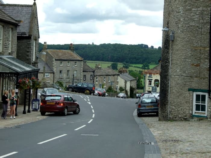 View of the Market Square approaching from the Coverham road. The castle is set back at the right, ahead is the road to Masham, Bedale and Ripon. The road to Leyburn is to the left, downhill to the Ure bridge