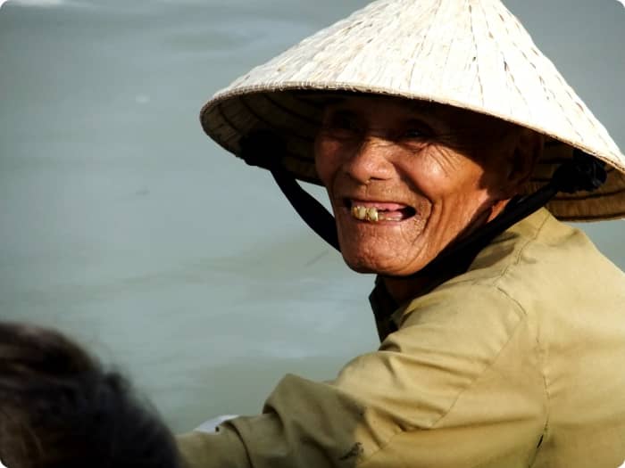 Travel to Hue Vietnam: A boatman wearing the traditional Vietnamese conical hat, waiting for tourist to get onto his boat