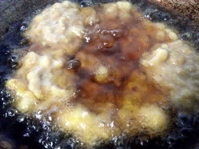 Scoop the cekodok mixture into the wok and fry one side until it is medium brown. You can fry four or five pieces at the same time.
