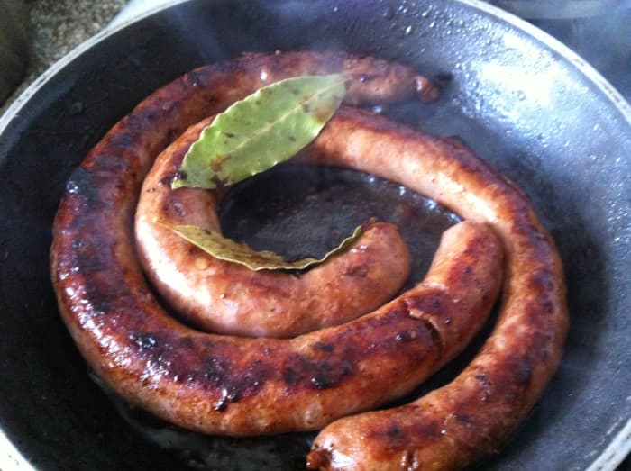 Italian Sausage (luganica) in the frying pan with bay leaves and a few drops of balsamic vinegar