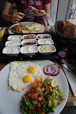 A yummy breakfast of sunny side up eggs and an assortment of cheeses and condiments,
